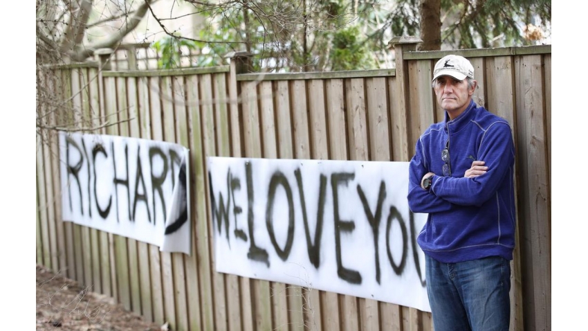 Richard Reid poses with a sign his family made for him when he was in the hospital. 