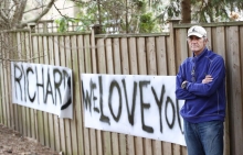 Richard Reid poses with a sign his family made for him when he was in the hospital. 